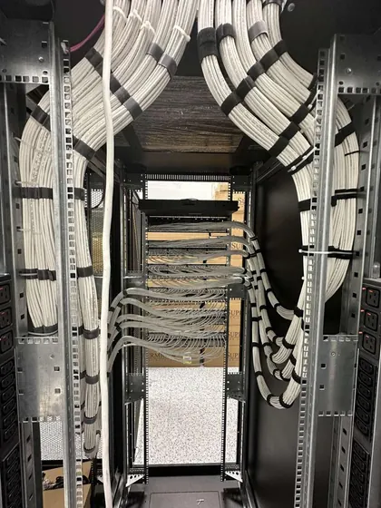 Interior of an equipment rack with copper cabling dressed in even curved bundles down both vertical managers to the patch panels