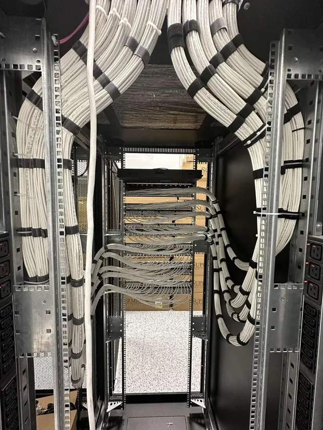 Interior of an equipment rack with copper cabling dressed in even curved bundles down both vertical managers to the patch panels