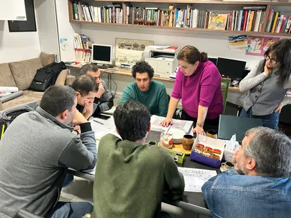 A review meeting in the STP office, papers on the table and a colleague presenting from the head of it