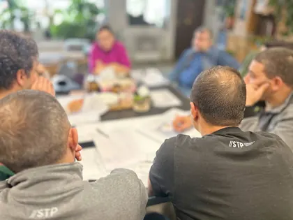 Members of the STP team around a long table in branded workwear, drawings spread between them